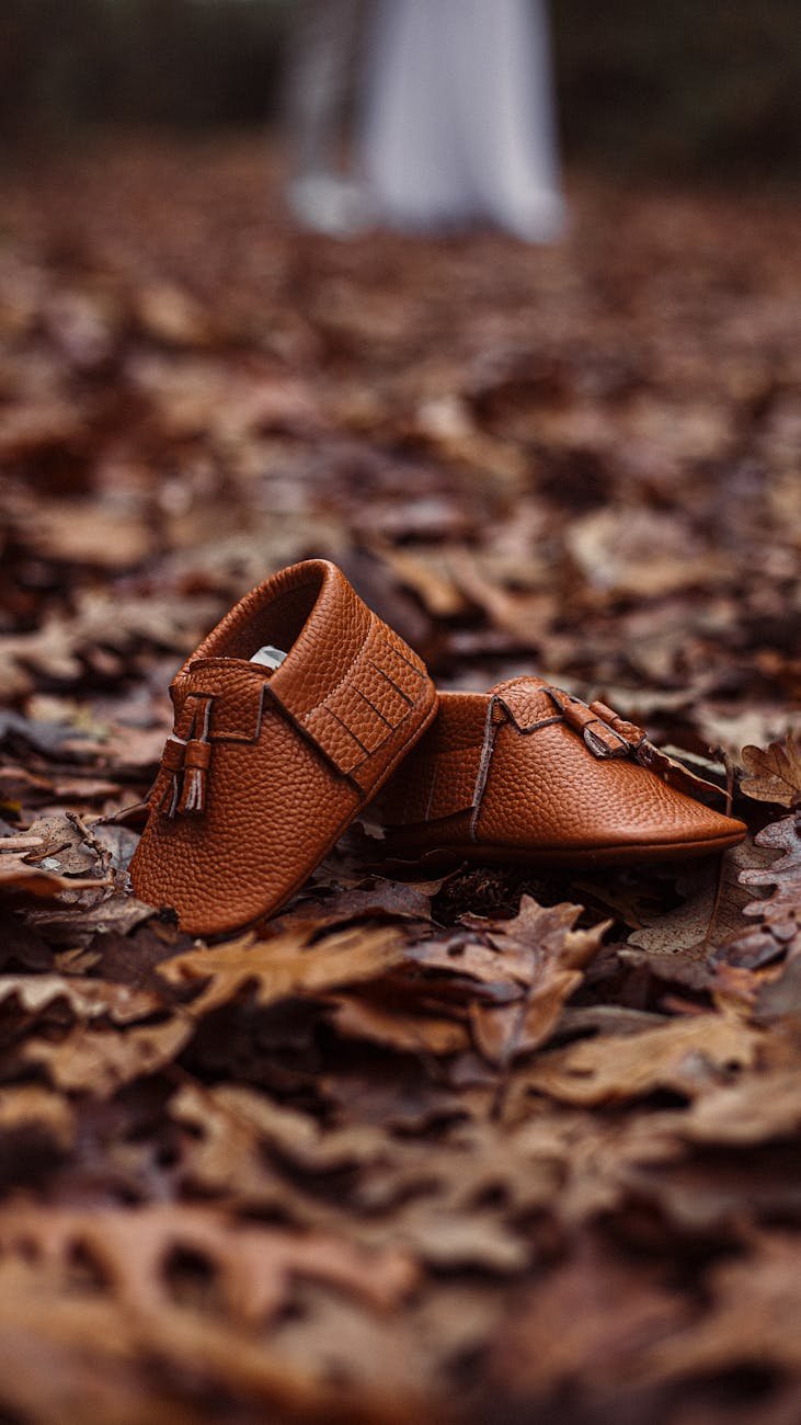 child shoes on autumn leaves