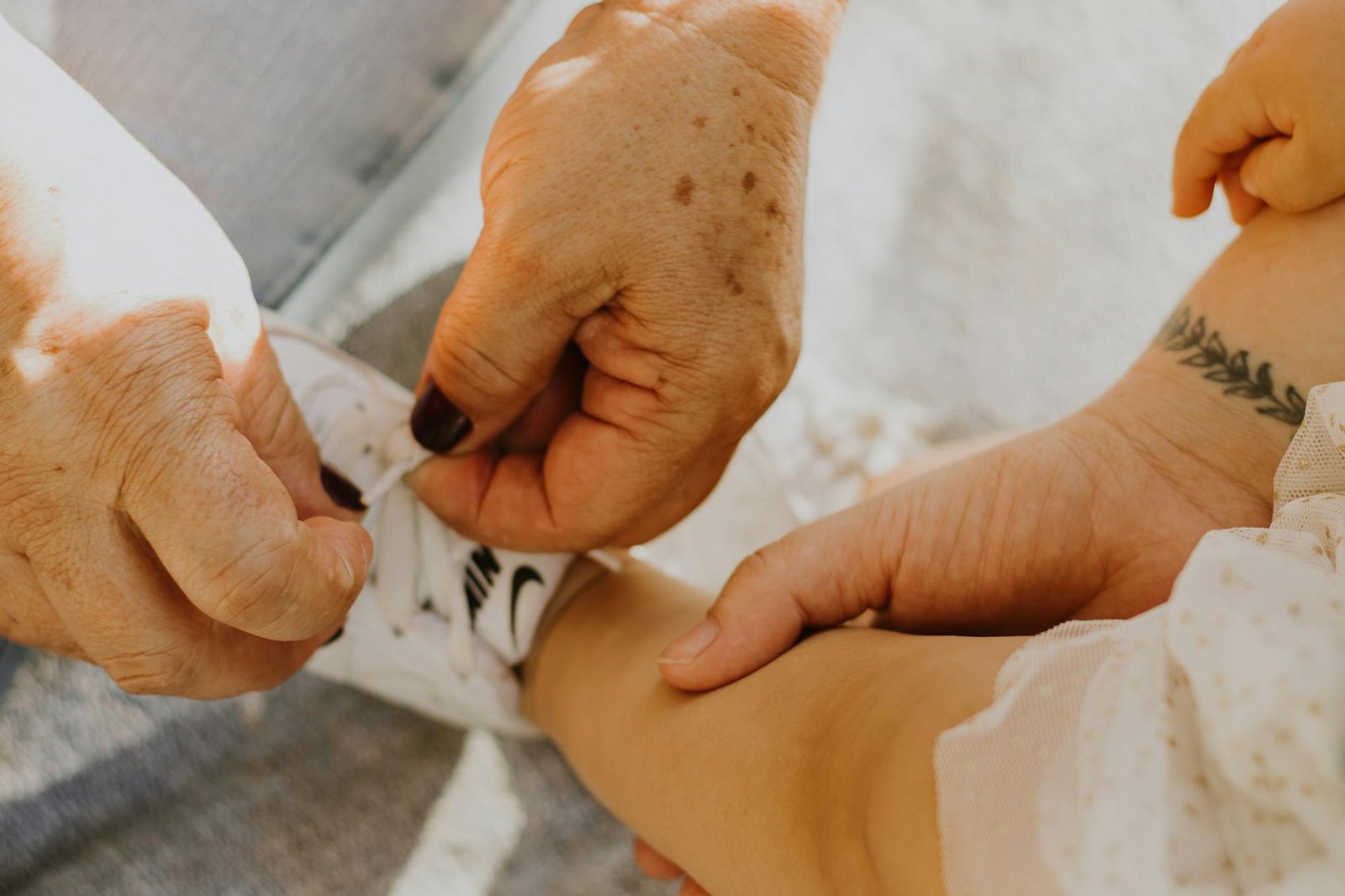 elderly person tying shoes of a baby